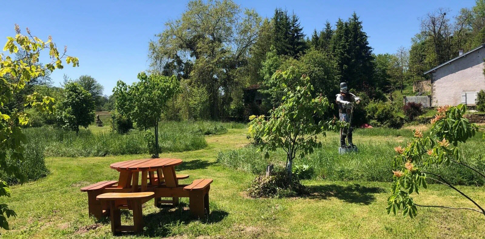 The Jardin des Marronniers: lawn, a picnic table and a sculpture among the trees