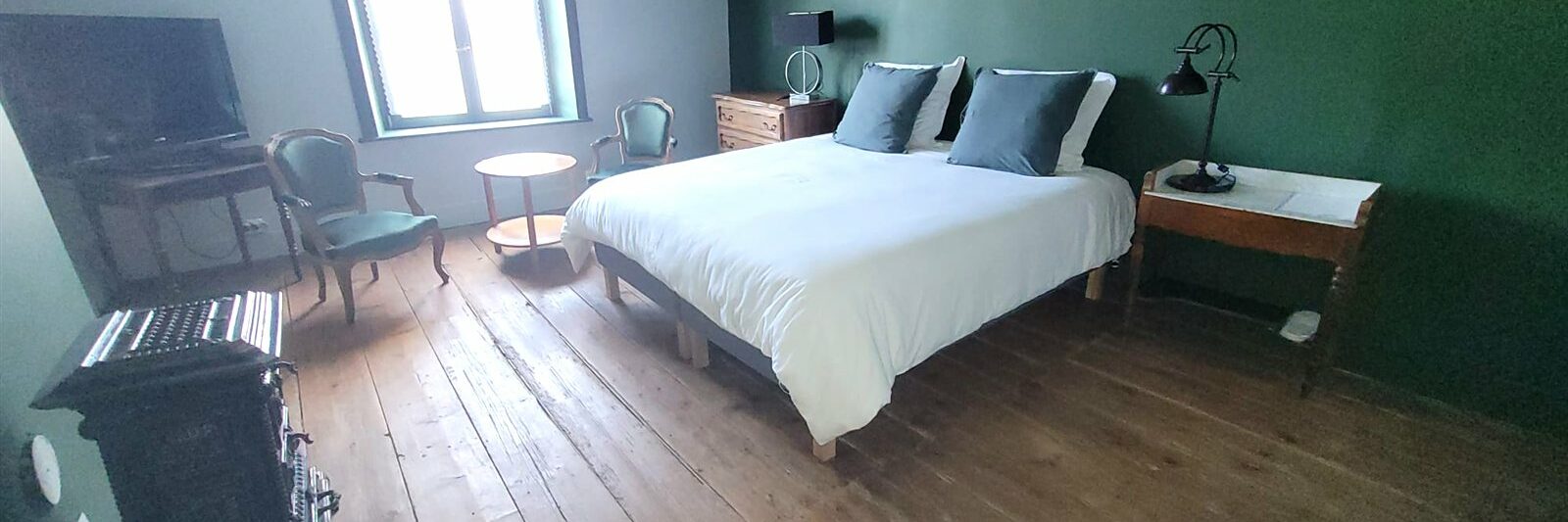 Chambre des Marchands Maison Cœurdacier Monthureux‑sur‑Saône Vosges — lit confortable, parquet, poêle en faïence et décoration chaleureuse.
