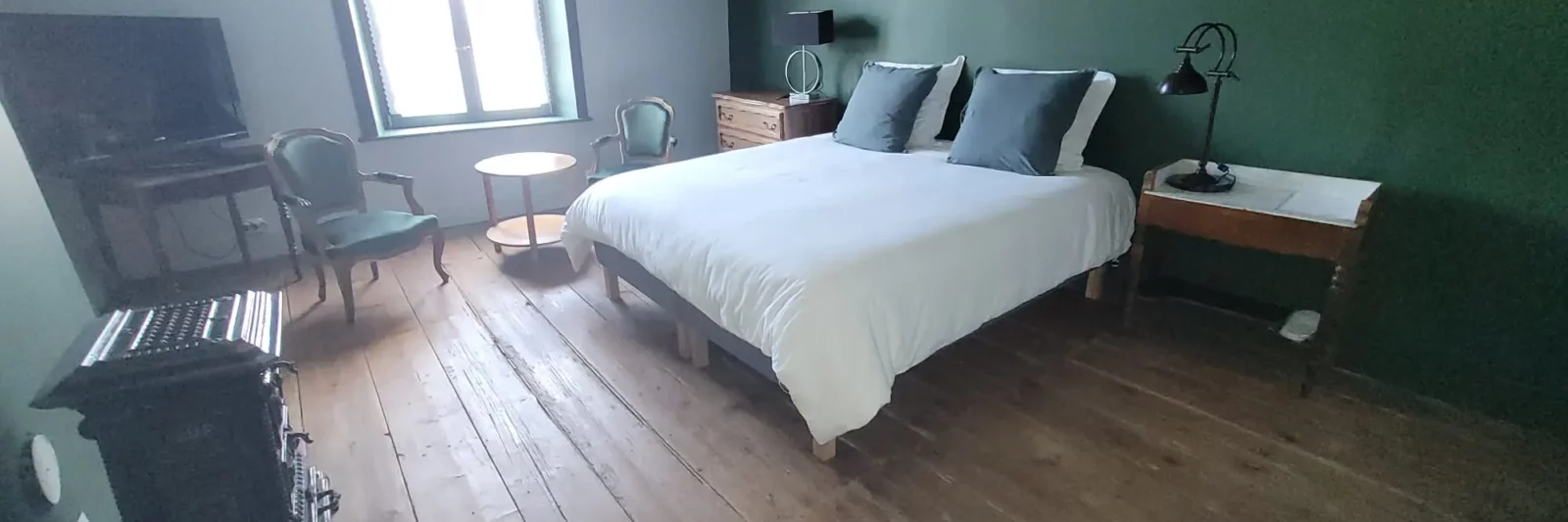 Chambre des Marchands Maison Cœurdacier Monthureux‑sur‑Saône Vosges — lit confortable, parquet, poêle en faïence et décoration chaleureuse.