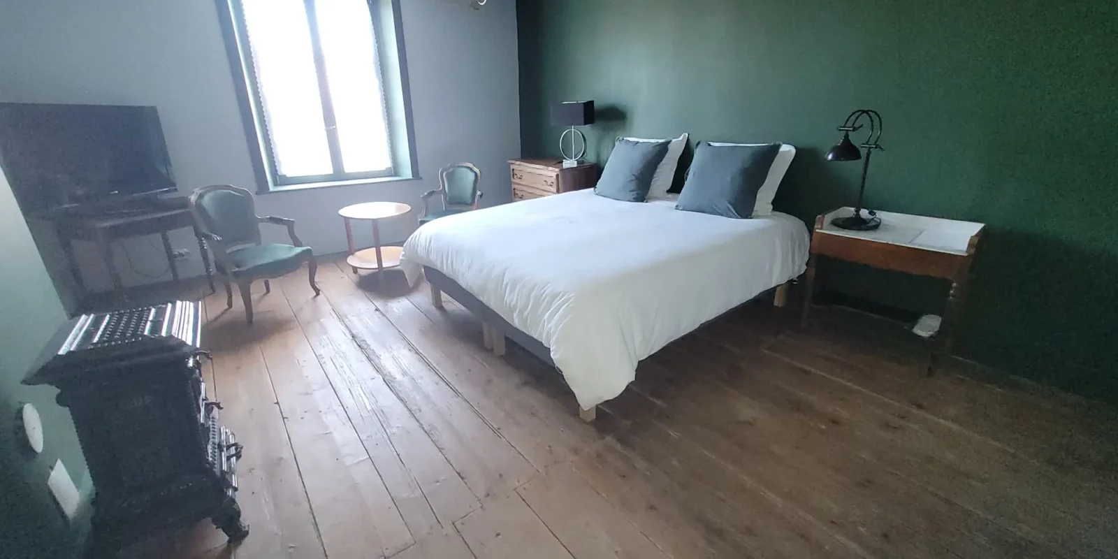 Chambre des Marchands Maison Cœurdacier Monthureux‑sur‑Saône Vosges — lit confortable, parquet, poêle en faïence et décoration chaleureuse.
