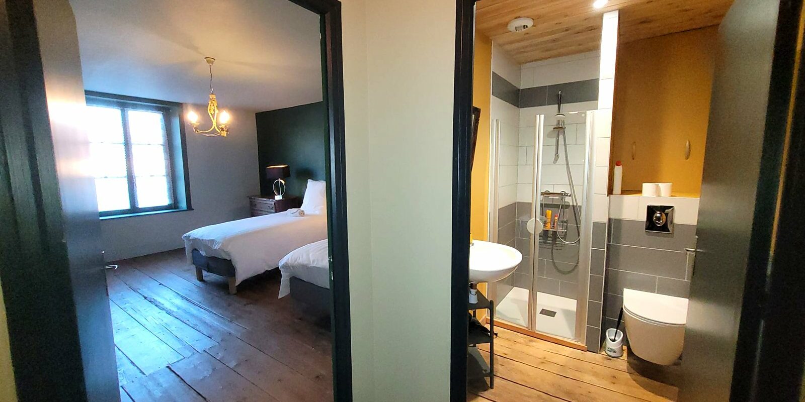 Chambre et salle de douche privative vues à travers deux portes ouvertes